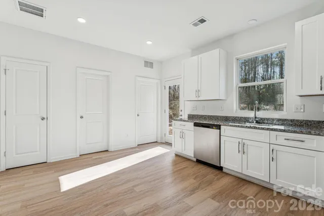 a kitchen with granite countertop white cabinets and wooden floor