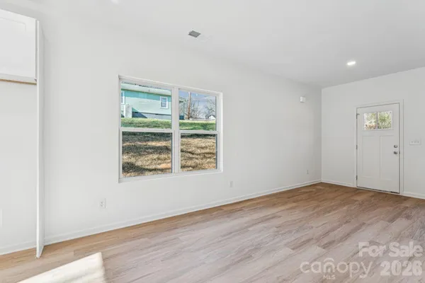 an empty room with wooden floor and windows