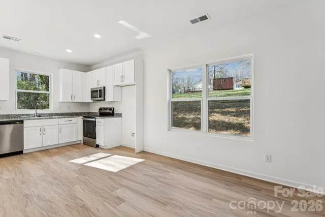 a kitchen with granite countertop white cabinets and white appliances