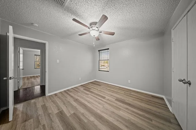 a view of empty room with wooden floor and fan