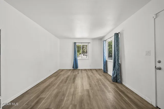 a view of an empty room with window and wooden floor