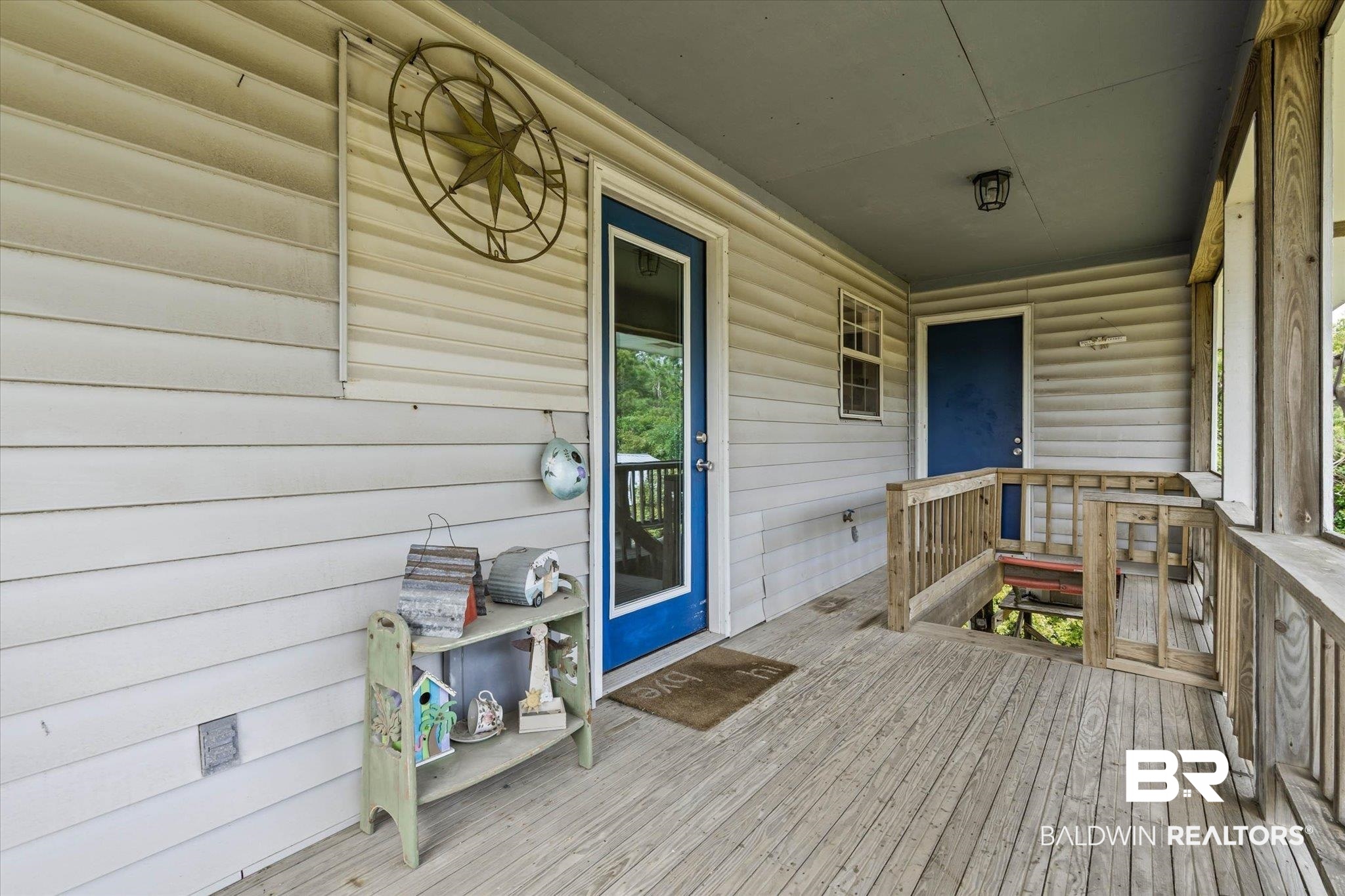 9100 Shell Belt Road Coden, AL 36523 - Photo 19 of 38 Expansive wood-finish porch featuring horizontal siding, a blue entry door, and a built-in outdoor staircase