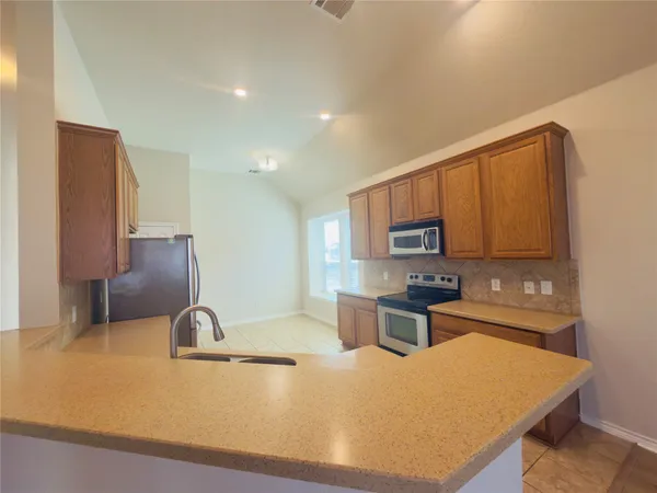 a kitchen with granite countertop a stove a sink and a microwave