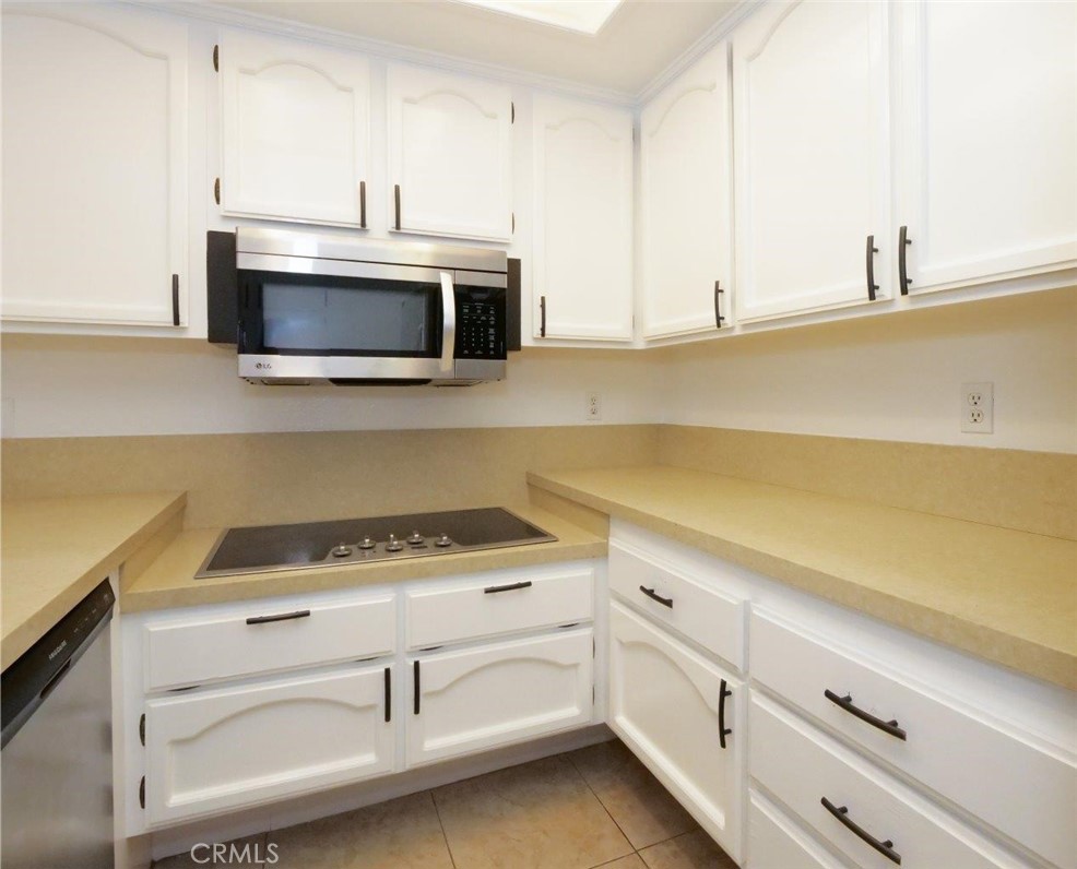 13601 Del Monte Drive, Unit 75 Seal Beach, CA 90740 - Photo 11 of 28 a kitchen with granite countertop white cabinets and white appliances