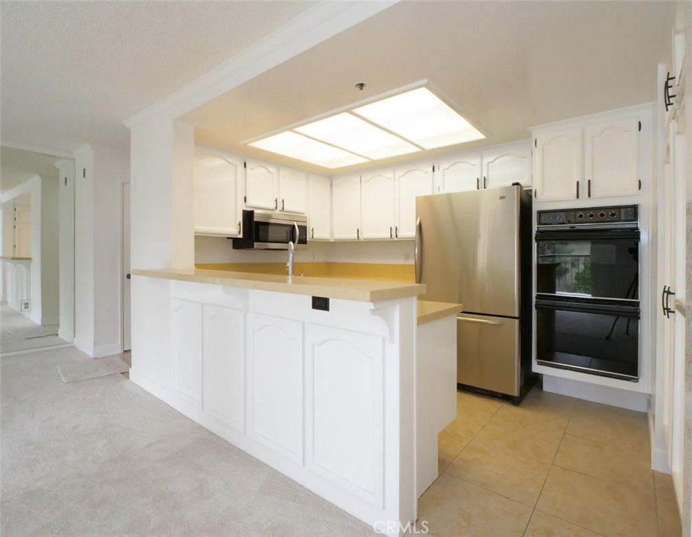 13601 Del Monte Drive, Unit 75 Seal Beach, CA 90740 - Photo 8 of 28 a kitchen with a refrigerator a microwave a stove and cabinets