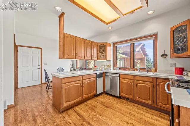 a kitchen with stainless steel appliances granite countertop a stove top oven a sink dishwasher and cabinets with wooden floor