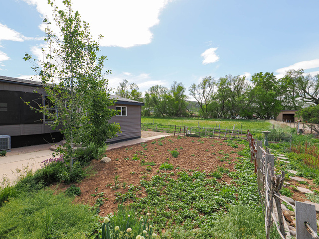 94 Spring Canyon Road Coalville, UT 84017 - Photo 8 of 50 Landscaped outdoor area featuring garden beds, a stone pathway, and a rustic wooden fence