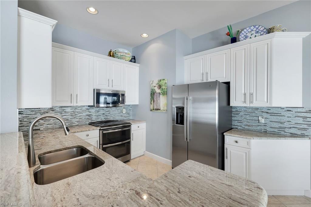 3232 Sundance Circle Naples, FL 34109 - Photo 14 of 50 a kitchen with stainless steel appliances granite countertop a sink stove and refrigerator