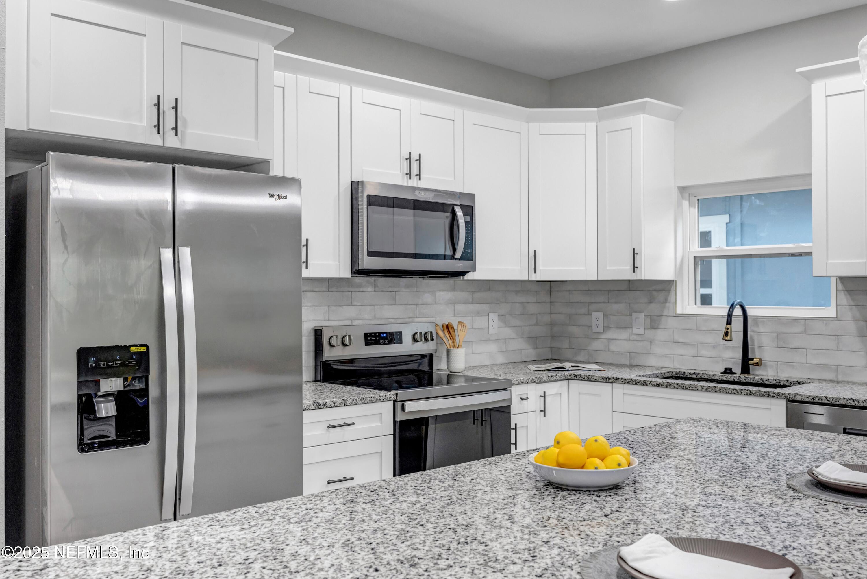 34 Delmonte Street Baldwin, FL 32234 - Photo 11 of 38 a kitchen with stainless steel appliances granite countertop a refrigerator a stove a sink and dishwasher with wooden floor