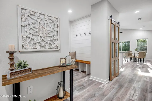 a kitchen with stainless steel appliances granite countertop a stove a sink a microwave a refrigerator and white cabinets with wooden floor