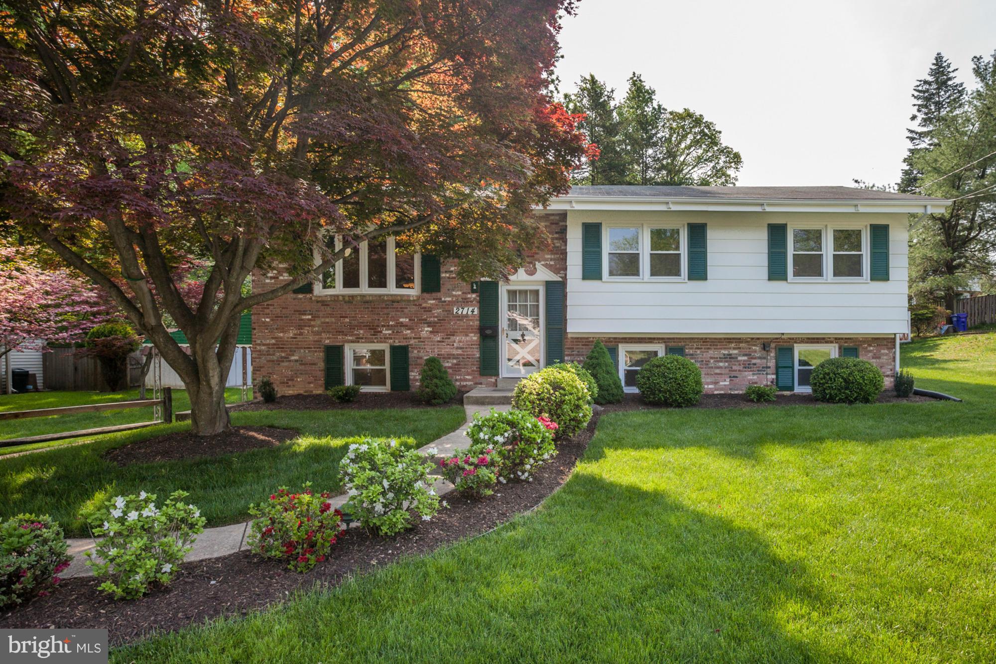 a front view of a house with a garden and trees
