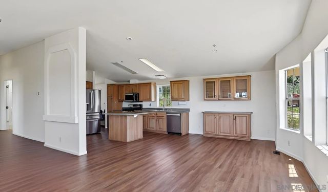 a open kitchen with a refrigerator and wooden floor
