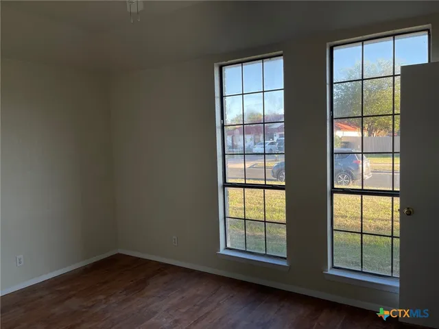 an empty room with wooden floor and windows