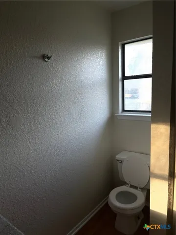 a white toilet sitting in a bathroom next to a window