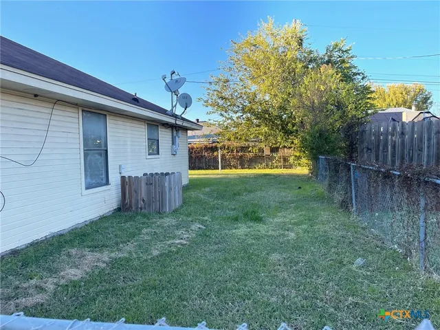 a view of backyard with wooden fence and large trees