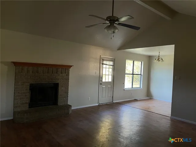 a view of an empty room with a fireplace and a window