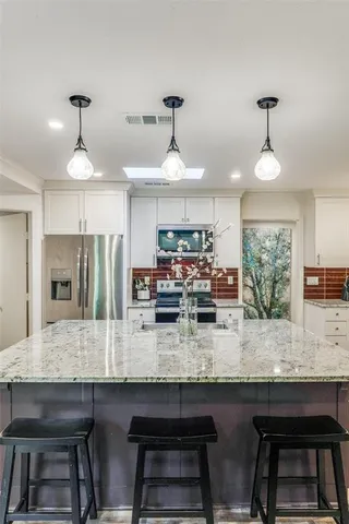 a kitchen with stainless steel appliances granite countertop a sink a stove and a refrigerator