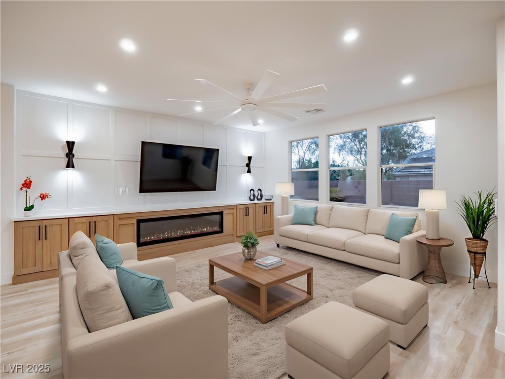 7870 Midnight Ride Street Las Vegas, NV 89131 - Photo 24 of 69 Living room with ceiling fan, light wood finished floors, a decorative wall, a glass covered fireplace, and recessed lighting