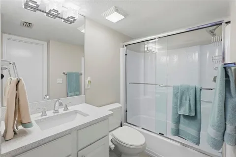 a bathroom with a shower sink vanity mirror and toilet