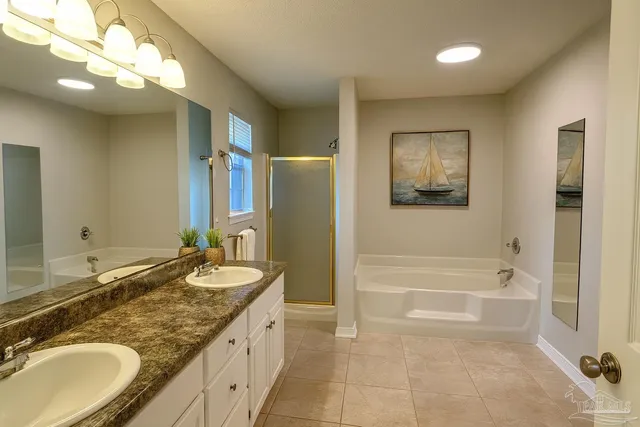 a bathroom with a granite countertop double vanity sink a mirror a bathtub and a shower