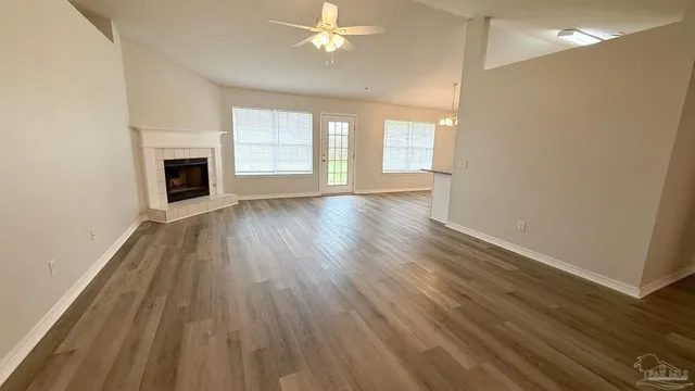 an empty room with wooden floor fireplace and windows