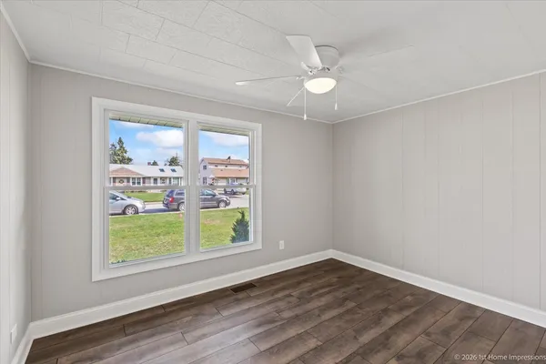 an empty room with wooden floor fan and window