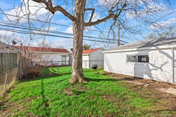 a view of a backyard with plants and large tree
