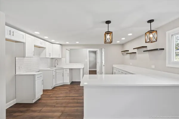 a large white kitchen with kitchen island a sink stainless steel appliances and cabinets