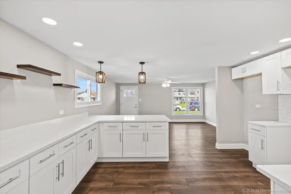 a large white kitchen with a lot of counter space and wooden floor