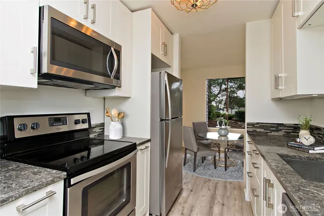 a kitchen with stainless steel appliances granite countertop a stove a microwave and a refrigerator