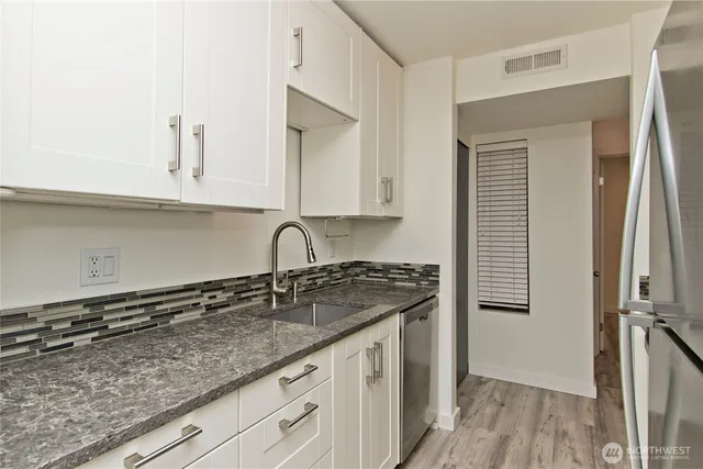 a kitchen with granite countertop a sink a stove and cabinets