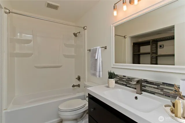 a bathroom with a sink a toilet a mirror and shower