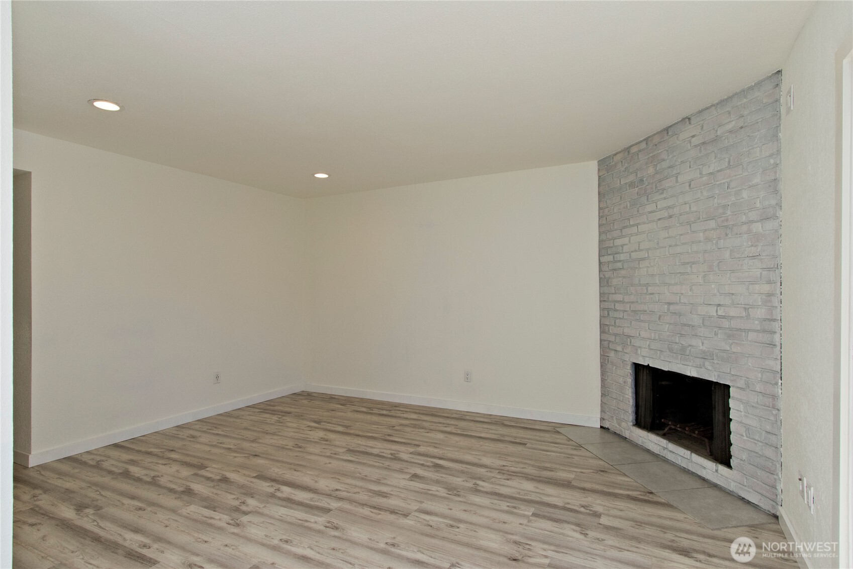 12515 Northeast 145th Place, Unit D127 Kirkland, WA 98034 - Photo 6 of 21 a view of empty room with wooden floor and fireplace