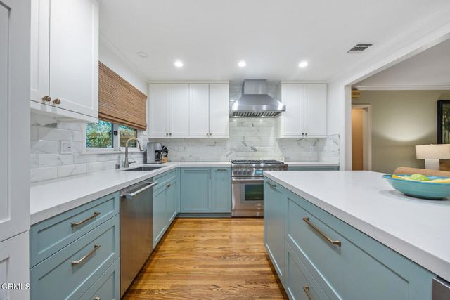 a kitchen with stainless steel appliances granite countertop a stove top oven a sink dishwasher and a fireplace with wooden floor