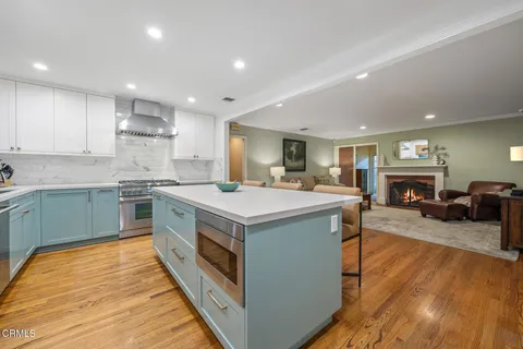 a large white kitchen with wooden floor and a sink