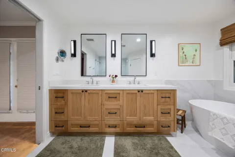 a spacious bathroom with a double vanity sink a large mirror and a bathtub