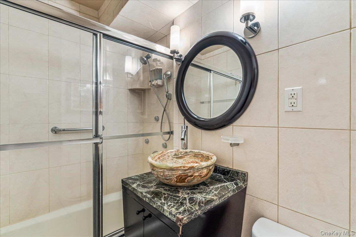 220-55 46th Avenue, Unit 5P Queens, NY 11361 - Photo 15 of 24 a bathroom with a granite countertop sink a mirror and a shower