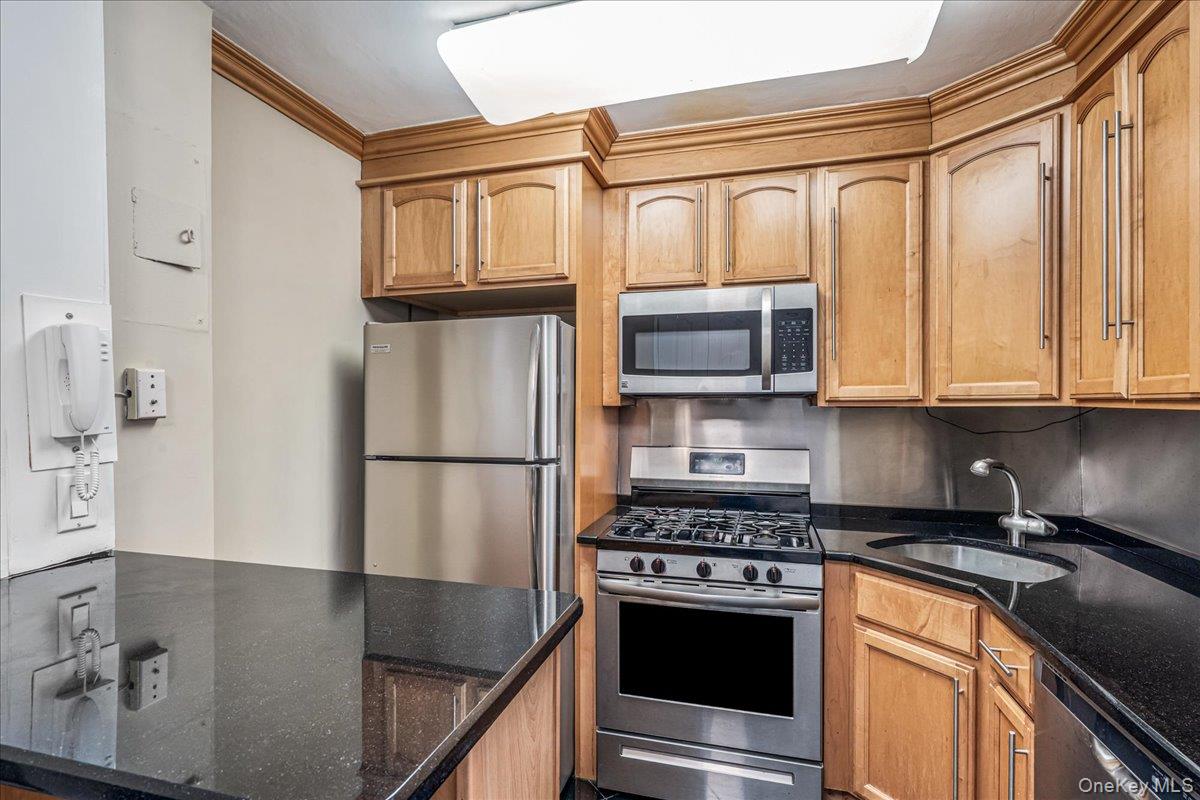 220-55 46th Avenue, Unit 5P Queens, NY 11361 - Photo 5 of 24 a kitchen with stainless steel appliances granite countertop a refrigerator a stove and a sink with wooden floor