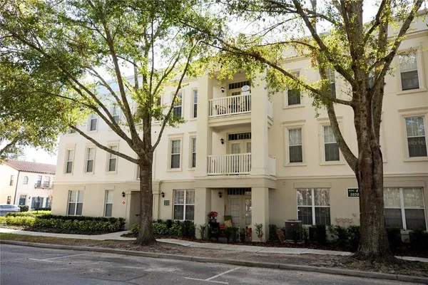 a view of a white house with a large tree tree front of it