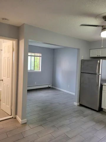 a view of a refrigerator in kitchen and an empty room with windows