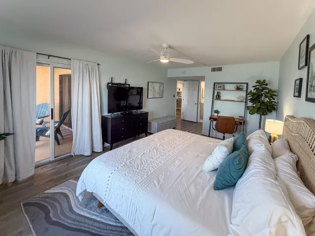 a bedroom with a large bed a flat tv screen and dresser