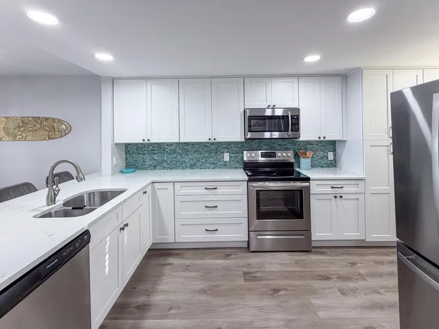 a kitchen with stainless steel appliances granite countertop a stove a sink and a refrigerator