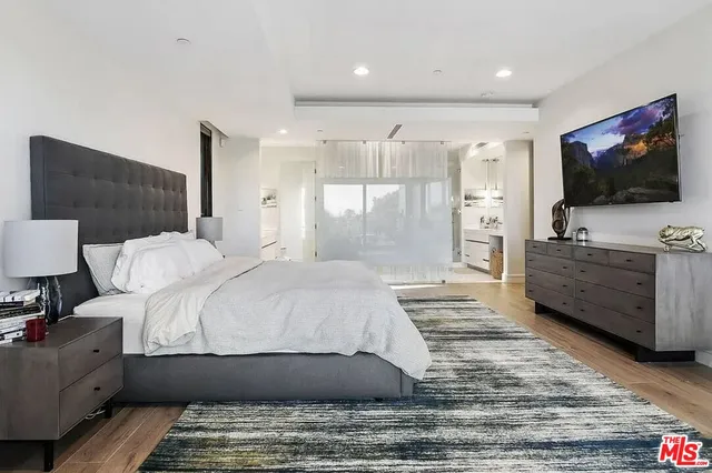 a spacious bedroom with a bed and a flat screen tv