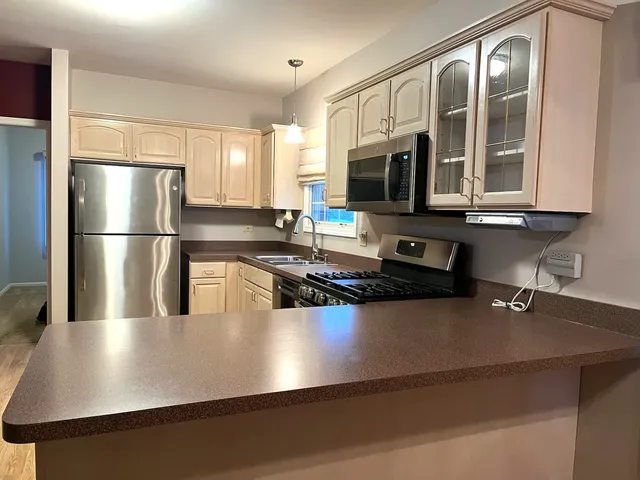 a kitchen with a refrigerator a stove a sink a counter space and cabinets