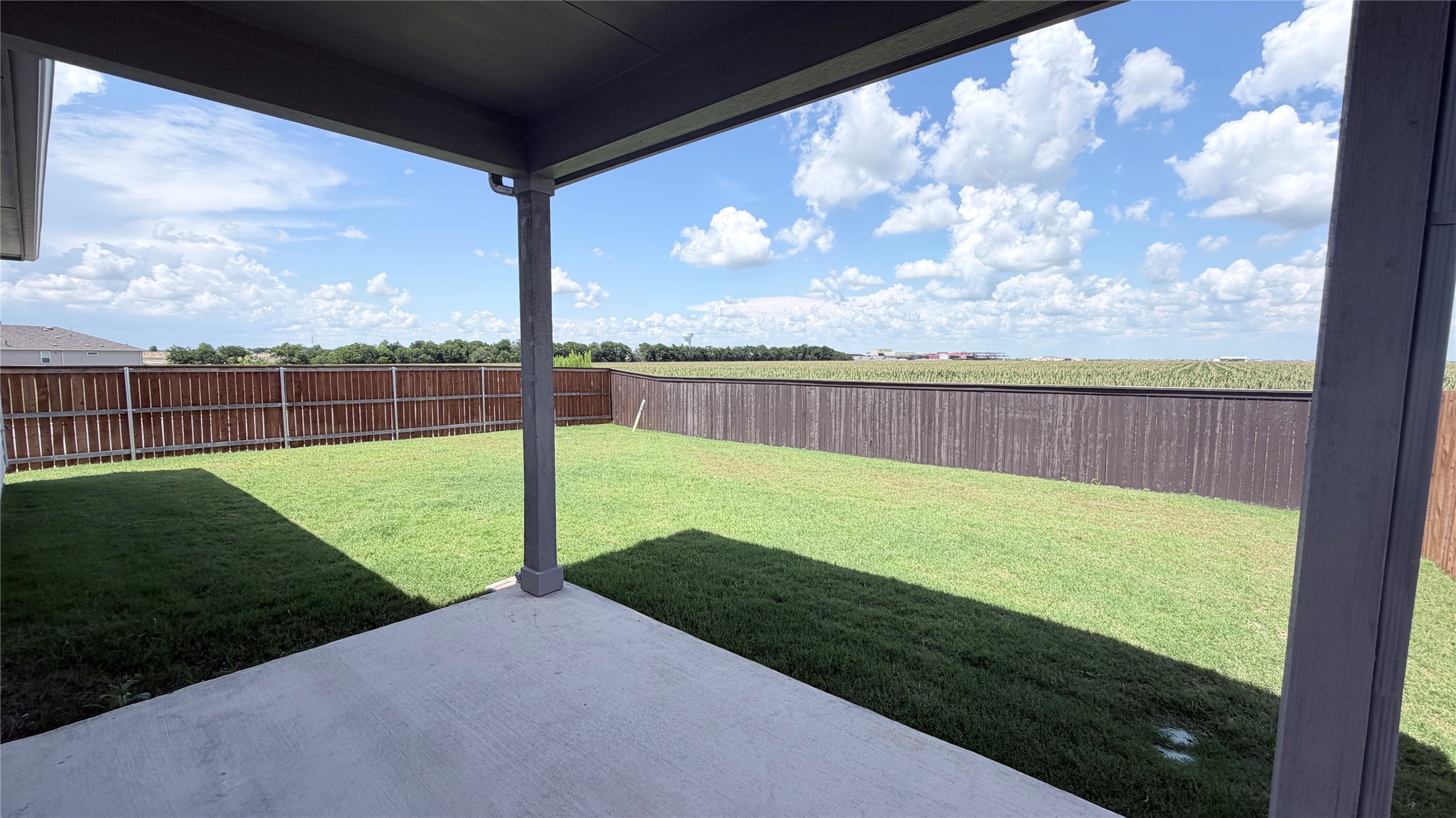 2001 Wynn Road Hutto, TX 78634 - Photo 34 of 39 A spacious backyard with lush green grass, a privacy fence, and an inviting covered patio for outdoor enjoyment.