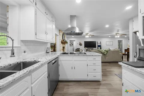 a kitchen with stainless steel appliances granite countertop a refrigerator a sink a stove and oven a wooden floor