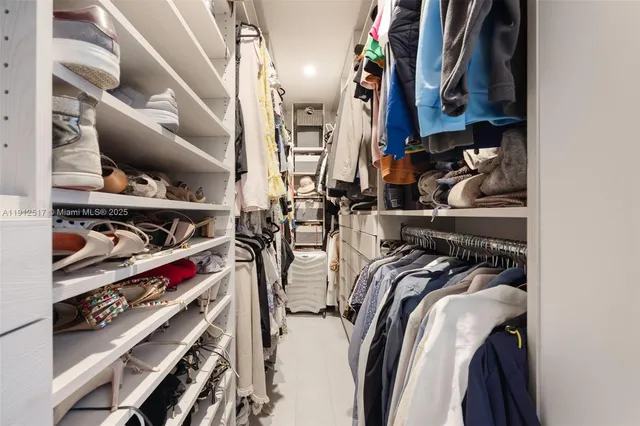 a view of walk in closet with clothes and shoes