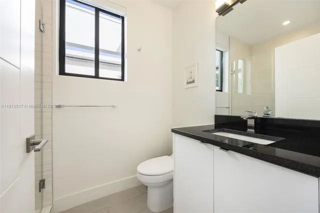a bathroom with a granite countertop sink toilet and a mirror