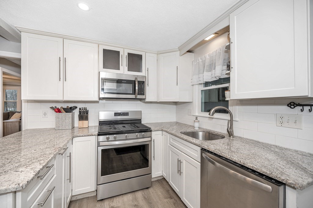 76 Maplewood Drive Townsend, MA 01469 - Photo 8 of 31 a kitchen with granite countertop a sink dishwasher stove and microwave with wooden floor