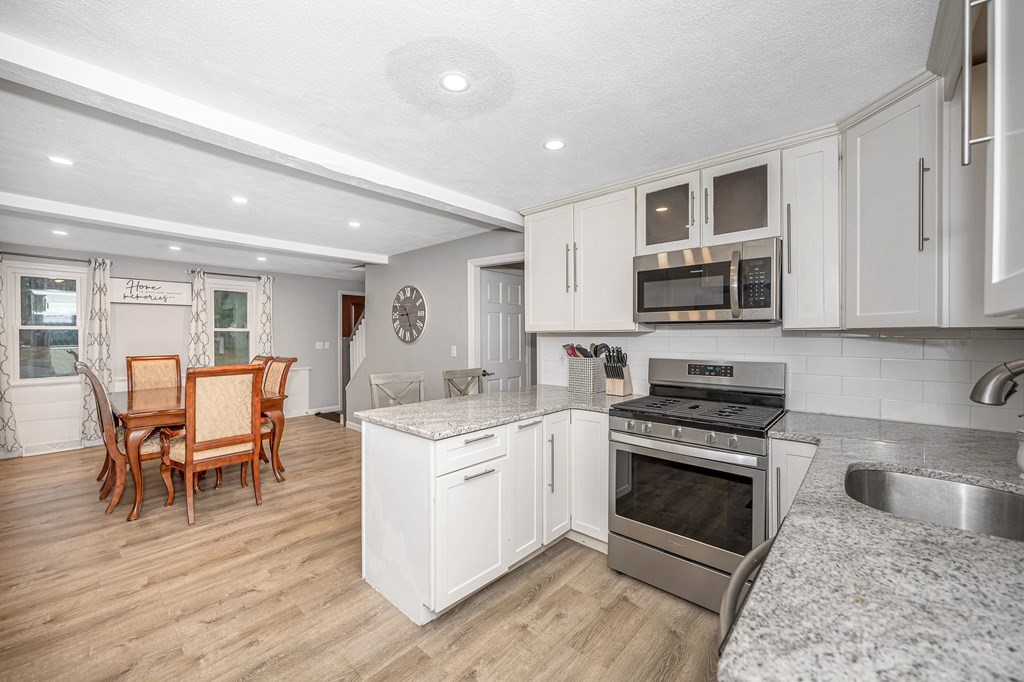 76 Maplewood Drive Townsend, MA 01469 - Photo 9 of 31 a kitchen with stainless steel appliances granite countertop a stove top oven a sink dishwasher a dining table and chairs with wooden floor